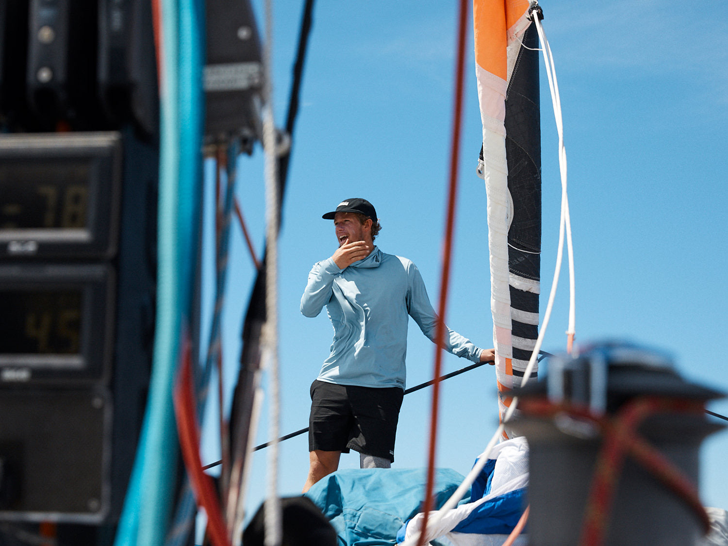 John Florence standing on a sail boat, with ropes and sails in the foreground