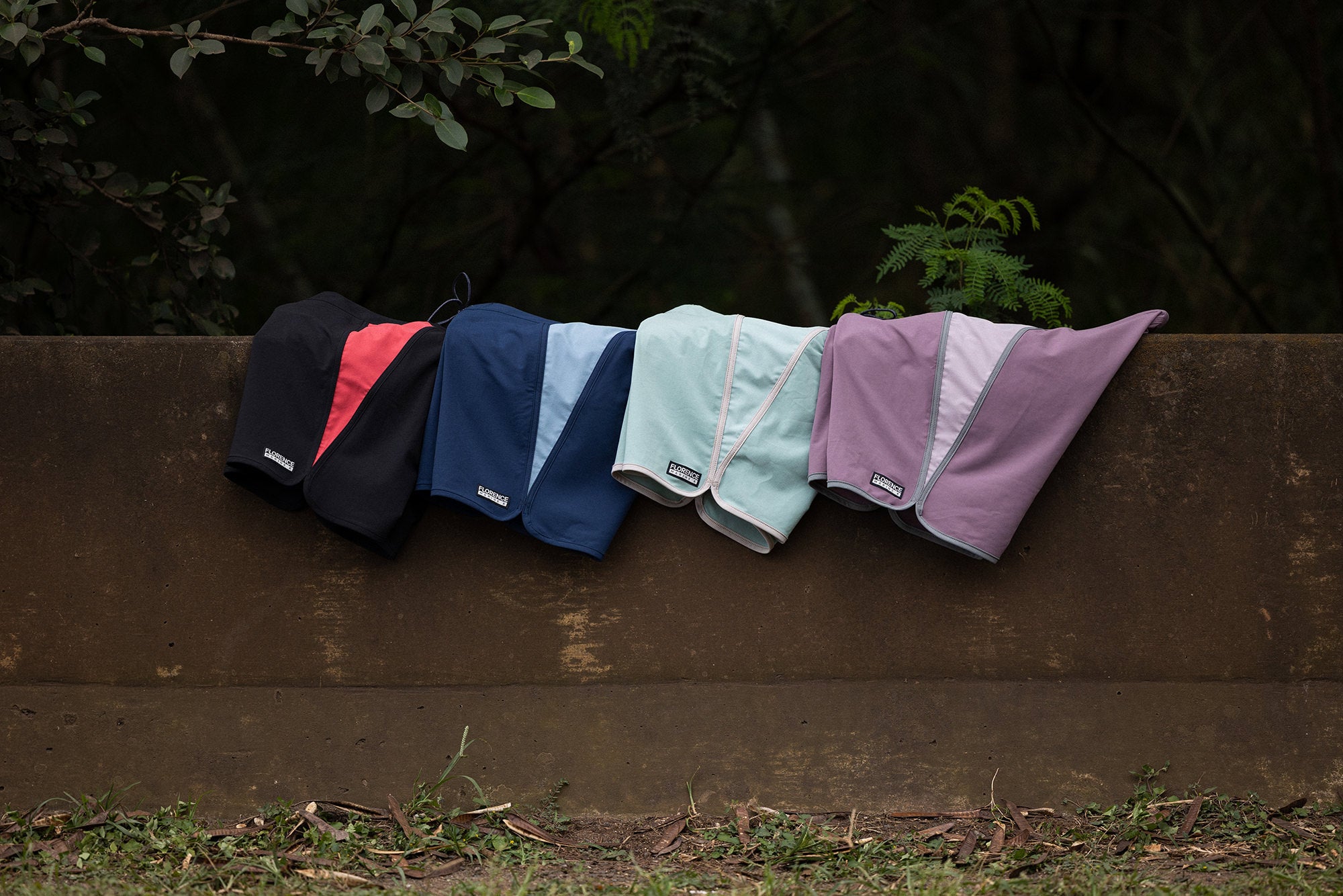 Four pairs of Florence Boardshorts resting on a railing on the side of the road