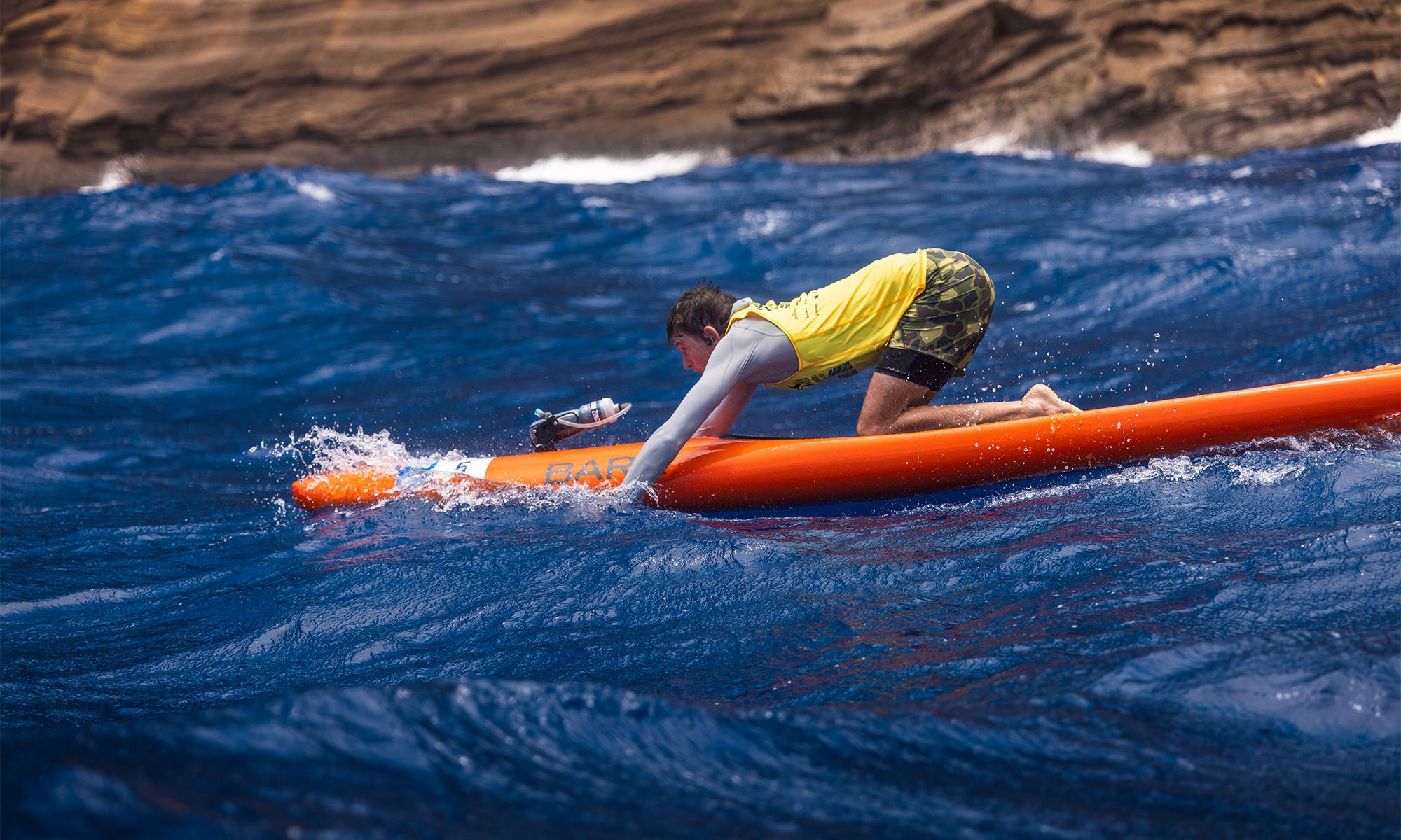 Lachie Lansdown in rashguard and boardshorts knee paddling on a prone paddle board by Portlock, Oahu