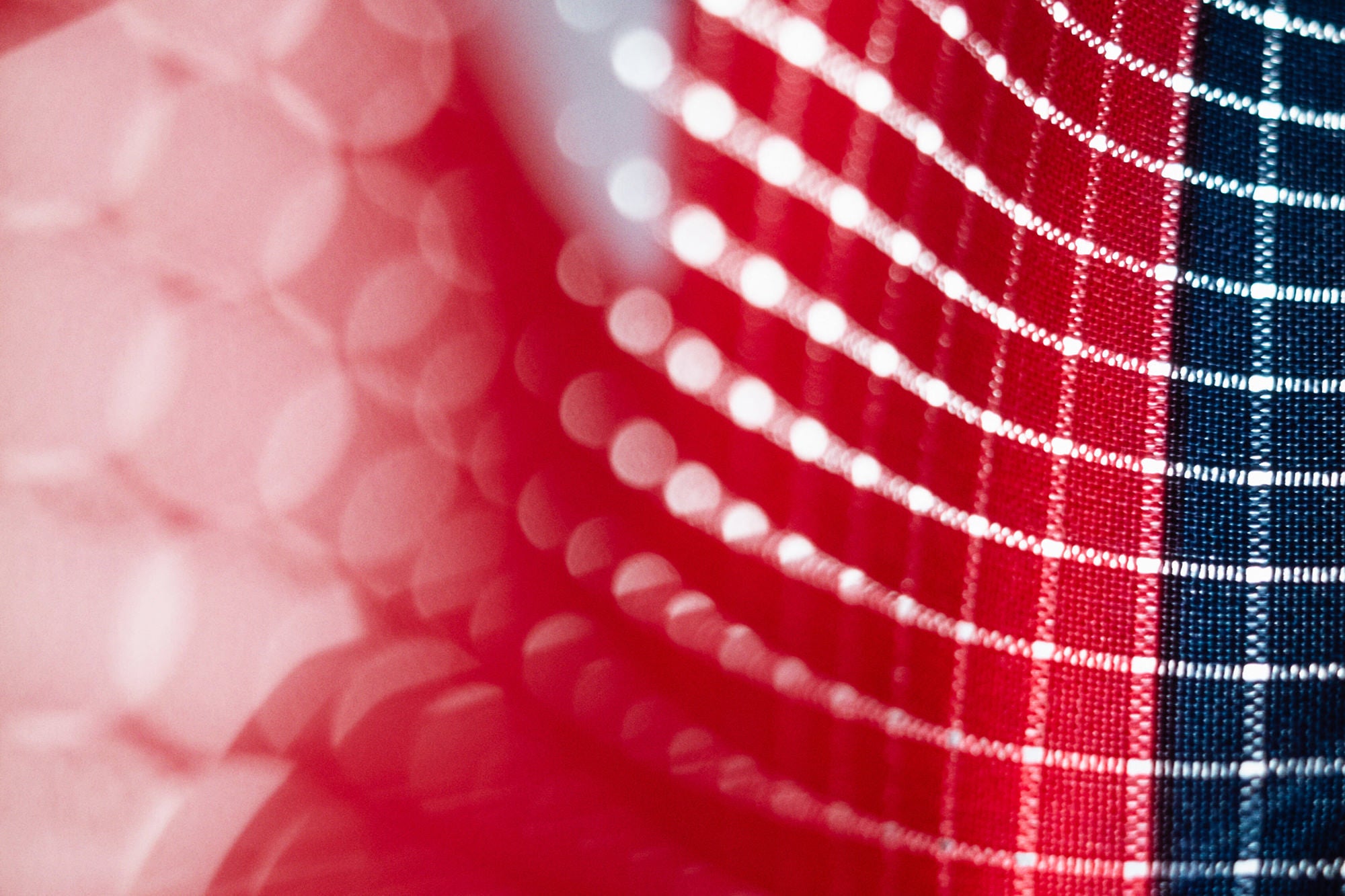 Up close shot of red and blue fabric with perforations and light shining through the perforations