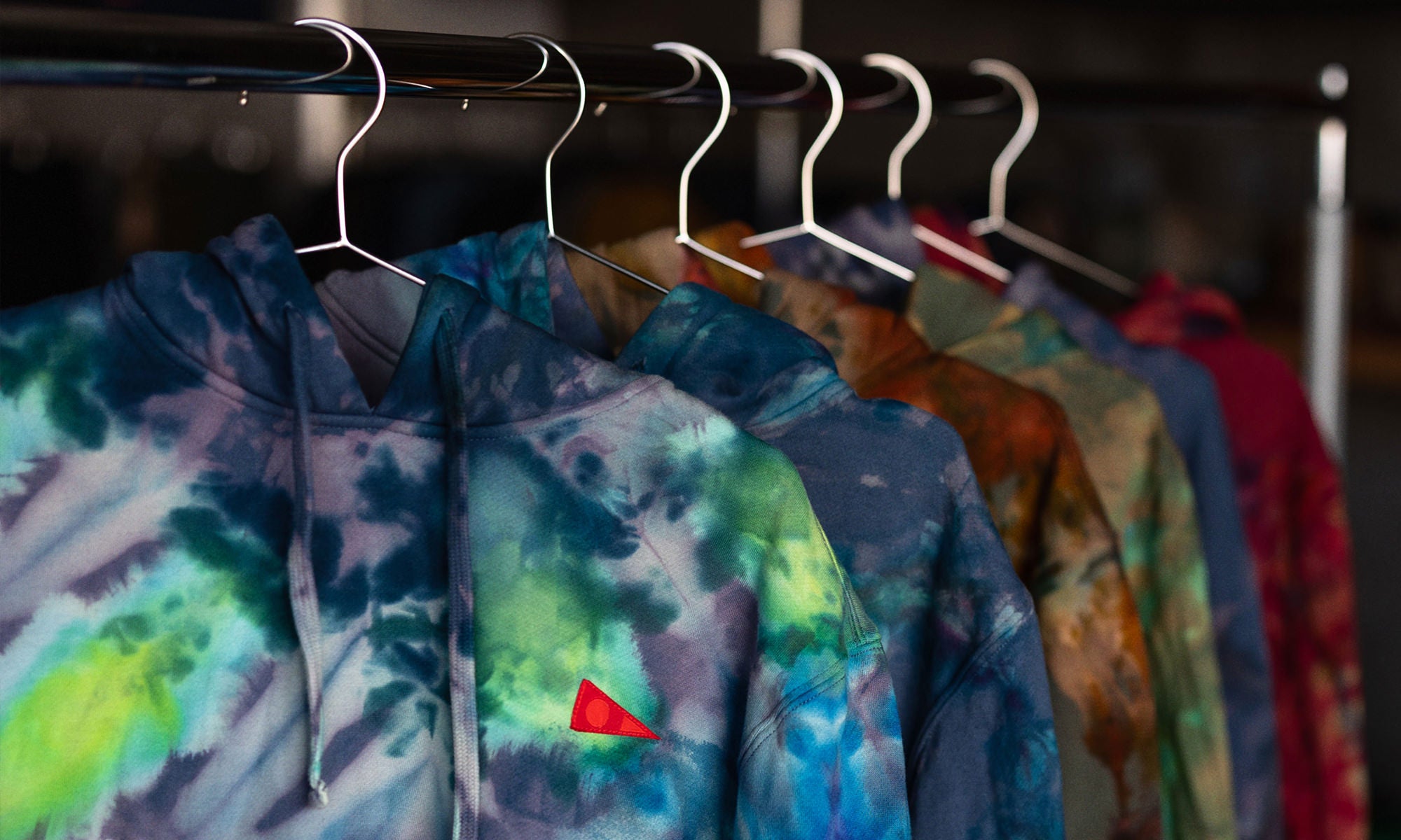 Six multicolor tie dye Florence sweatshirts hanging on hangers