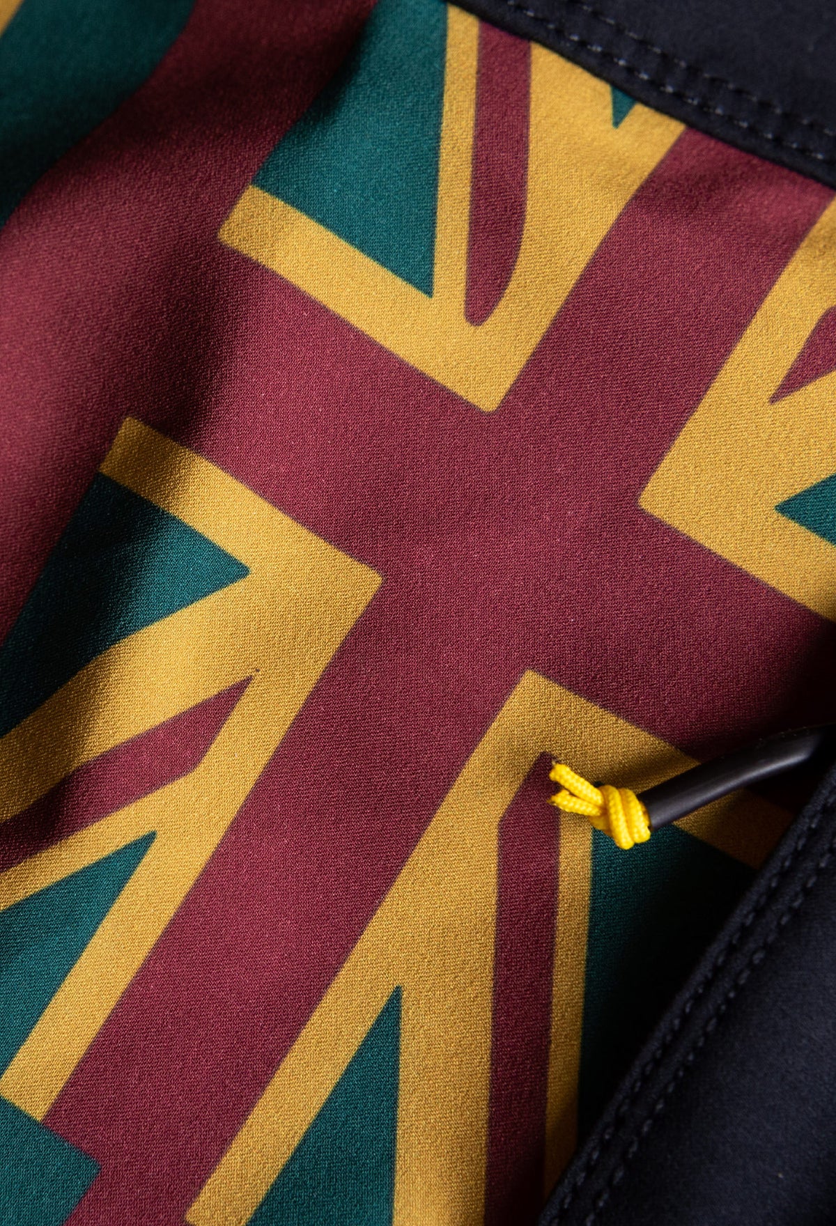 Zoomed in close up of the fabric on the side panel of a boardshort with a red, yellow and green Hawaiian Flag