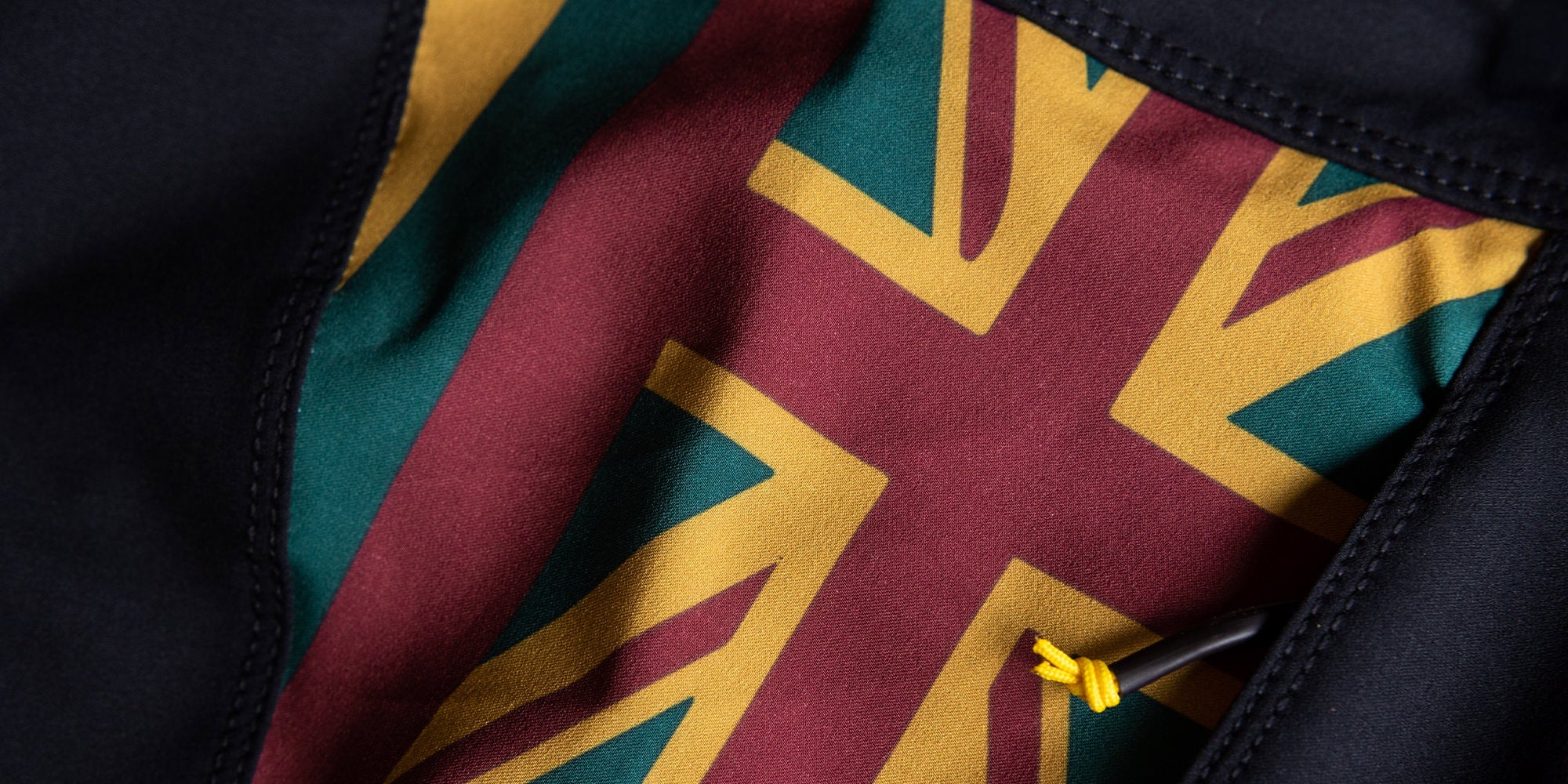 Zoomed in close up of the fabric on the side panel of a boardshort with a red, yellow and green Hawaiian Flag